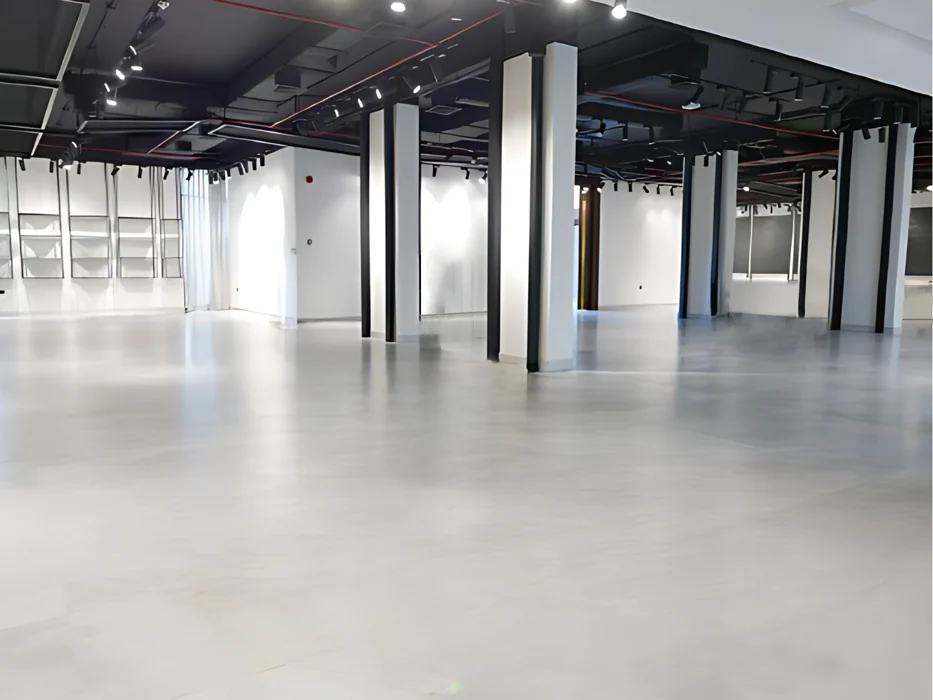 Edited interior image of an empty exhibition hall with dark columns and exposed ceiling.