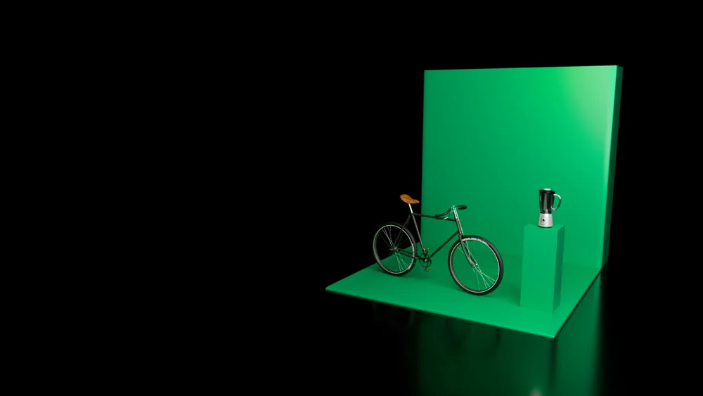 Bicycle and blender arranged on a green exhibition platform with a tall backdrop.